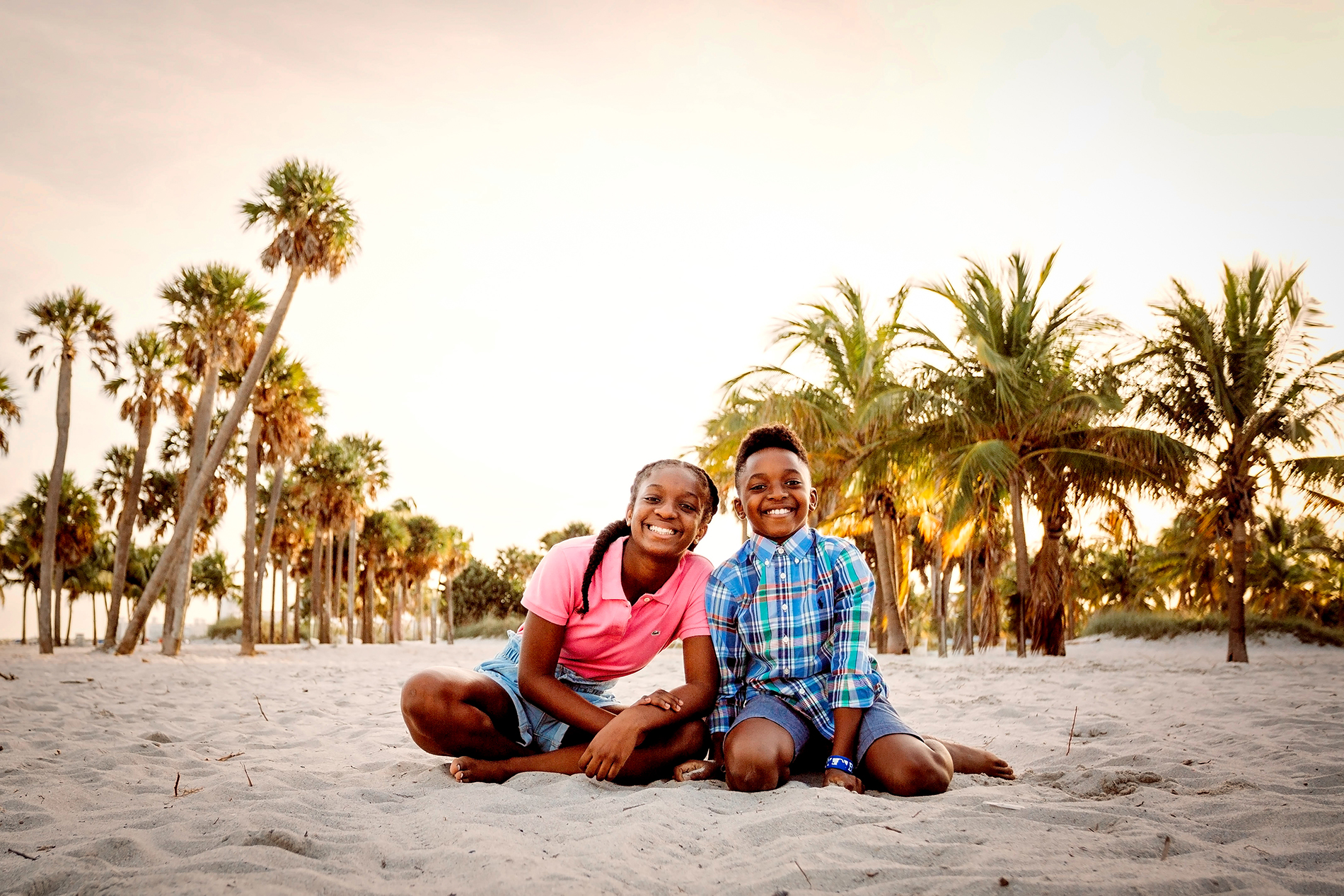 two siblings sitting on the sand
